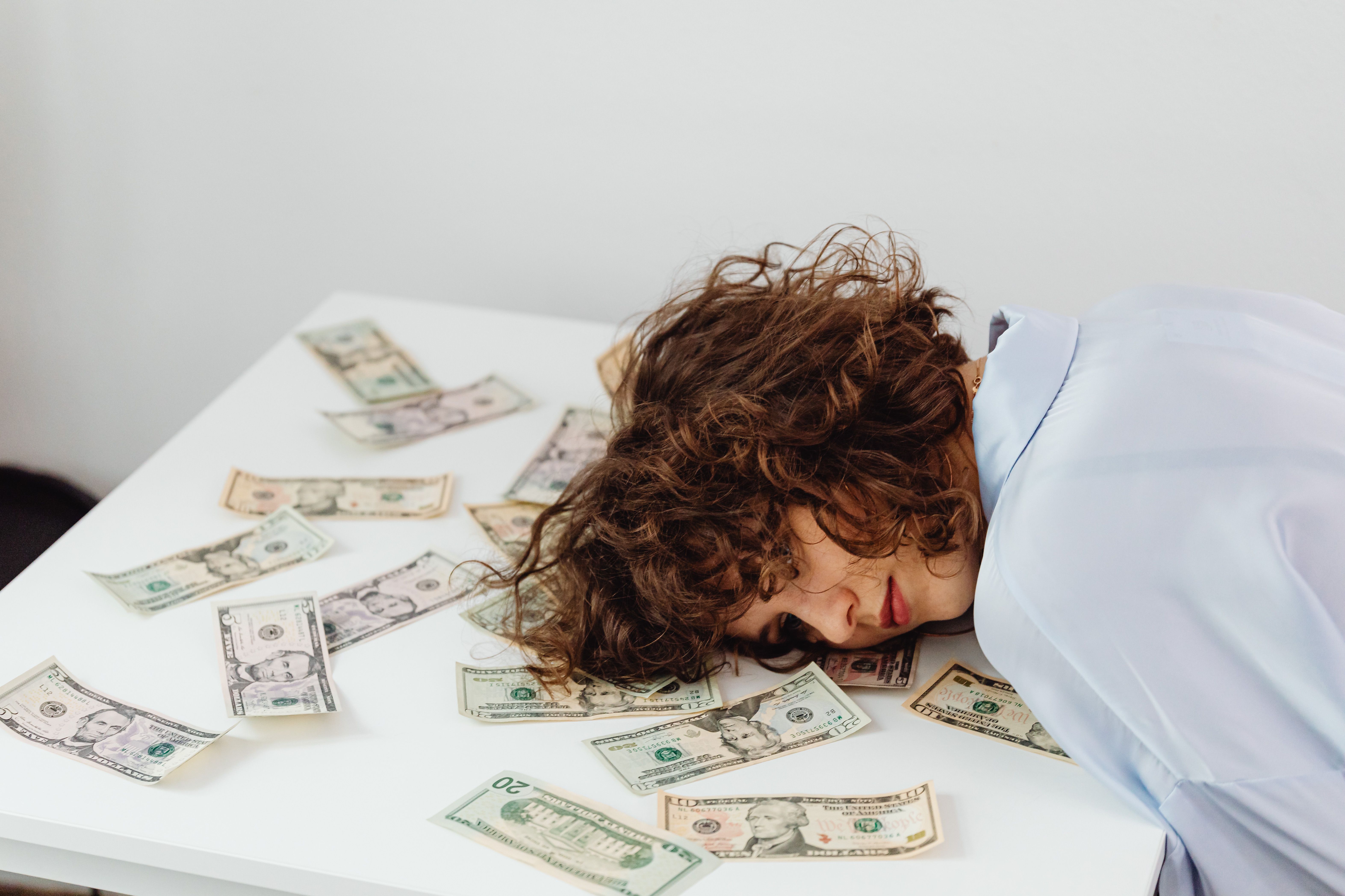 Mujer agotada sobre billetes — gasto en salud hormonal
